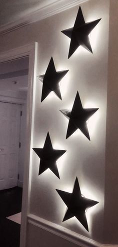 five black stars are mounted on the wall in front of a white door with light coming from it