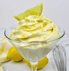 a glass bowl filled with whipped cream and lemon wedges