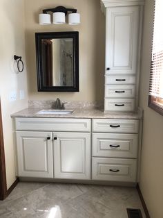 a bathroom with white cabinets and marble counter tops