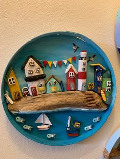 a plate with houses and boats painted on it next to a wall hanging from the ceiling