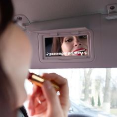 a woman is looking at her reflection in the rear view mirror while she brushes her teeth