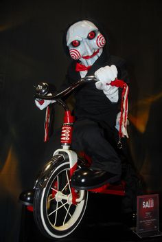 a creepy clown riding a small bike on display