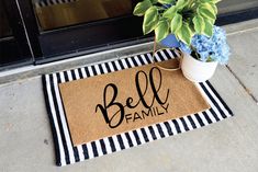 a door mat with the word bell family on it next to a potted plant