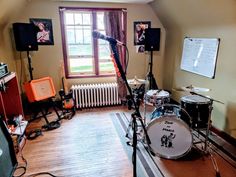 a recording studio with drums, microphones and other musical equipment in it's corner