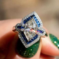 a diamond and blue sapphire engagement ring on someone's finger with green nail polish