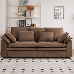 a brown couch sitting on top of a white floor next to a book shelf filled with books