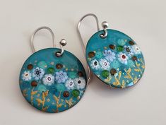 two blue earrings with flowers painted on them