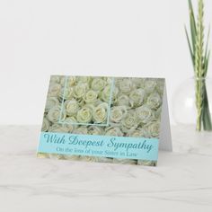 a card with white roses on it sitting next to a vase