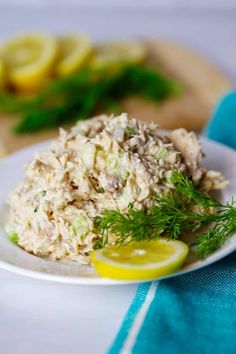 a white plate topped with tuna salad next to sliced lemons