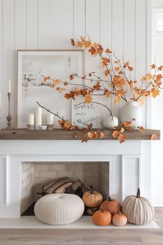 a white fireplace with pumpkins and candles on the mantel in front of it