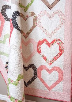 a heart quilt hanging on the side of a wall