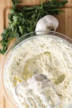 a bowl filled with white sauce next to some parsley