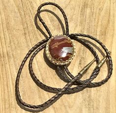 This is a Red Ocean Jasper Bolo Tie. The oval cabochon is 42.0 mm long and 32 mm wide. The slide is gold colored metal that measures 52.0 mm long and 42.0 mm wide. The bolo cord is twisted real leather that measures 36". The golden tips are gold colored metal. Brown Bolo Ties As A Gift, Brown Bolo Tie For Gift, Adjustable Southwestern Bolo Tie, Mens Western, Red Ocean, Western Accessories, Bolo Tie, Neck Ties, Ocean Jasper