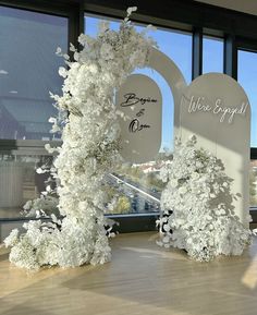 white flowers are on display in front of large windows