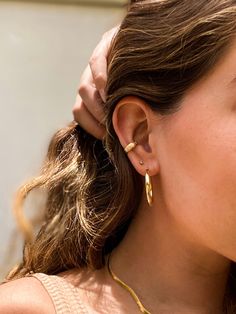 a close up of a person wearing some kind of gold earring on her left ear