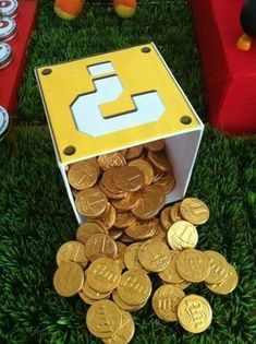 a bunch of gold coins sitting in the grass next to a yellow and white box