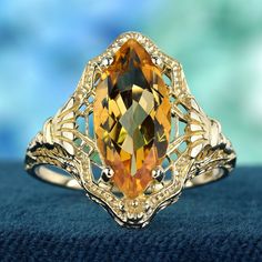 This vintage-inspired ring showcases a captivating marquise shaped citrine gemstone, its warm yellow hue reminiscent of a summer sun. Crafted in gleaming yellow gold, the ring features intricate filigree detailing that adds a touch of whimsical elegance. This enchanting ring is perfect for adding a touch of vintage glamour to any outfit. CHARACTERISTICS Status: Made to order Origin: Thailand Metal: Solid 9K Yellow Gold Ring Size: US 3-8 Total Gemstones Weight: 2.90 carat. (approx.) Total Gram We Filigree Ring Gold, Warm Yellow, Citrine Stone, Aquamarine Stone, Natural Citrine, Modern Ring, Citrine Gemstone, Gold Filigree, Filigree Ring