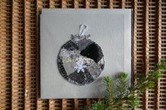 a christmas ornament hanging on a wall next to a pine tree and wicker mat