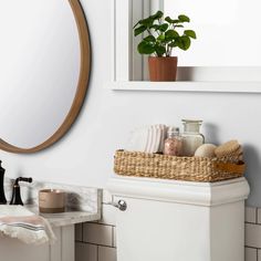 a white toilet sitting under a bathroom mirror next to a sink and a potted plant