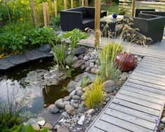 a wooden walkway leads to a small pond and seating area in the middle of a garden