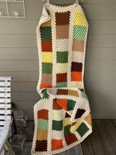 a crocheted blanket sitting on top of a wooden floor next to a wall