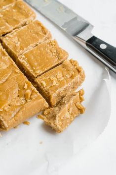 cut pieces of peanut butter fudge on a white plate with a knife next to it