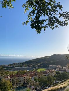 the sun shines brightly in front of an ocean view town and golf course, as seen from atop a hill