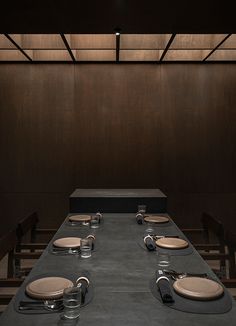 a long table with plates and silverware on it in front of a wooden wall