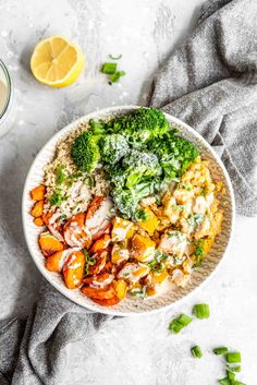 a bowl filled with rice, broccoli and carrots next to a glass of orange juice