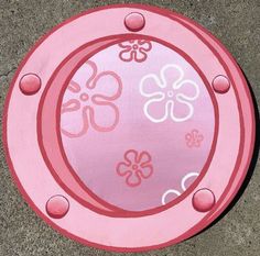 a pink frisbee laying on the ground with flowers painted on it's side