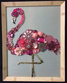 a pink flamingo made out of buttons and other assorted items in a wooden frame