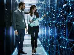 two people standing in a server room looking at something on the wall with blue lights