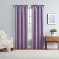 a living room with purple curtains and a white chair