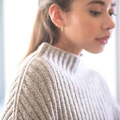 a woman wearing a sweater looking down at her cell phone