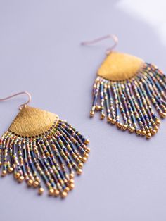 Embrace the celebration with the Confetti Fringe earrings! Each strand showcases a kaleidoscope of colors (blue, green, purple, pink), arranged in a playful confetti-like pattern. Adorning the ends of the fringe are shimmery gold drop beads. Draping from a brass fan shape, these earrings strike a balance between sophistication and bohemian charm. Their lively hues combine with captivating movement, making them a perfect choice for when you’re feeling carefree and spirited. Materials - Miyuki gla Multicolor Dangle Beaded Earrings For Celebrations, Multicolor Beaded Drop Earrings For Celebration, Multicolor Festive Jewelry With Ear Wire, Festive Multicolor Jewelry With Ear Wire, Rainbow Party Jewelry With Dangling Beads, Rainbow Dangling Beads Earrings For Party, Multicolor Dangling Beads Earrings For Celebration, Blue Dangling Beads Earrings For Celebration, Multicolor Dangle Chandelier Earrings For Celebration