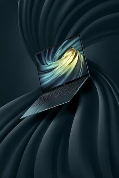 an open laptop computer sitting on top of a black surface with swirly lines in the background