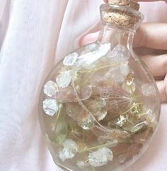 a person holding a glass bottle filled with flowers