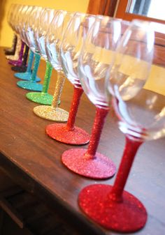 there are many wine glasses lined up on the table with red, green, yellow and blue glitters