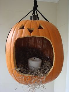 a pumpkin hanging from the ceiling with a candle in it's mouth and hay inside