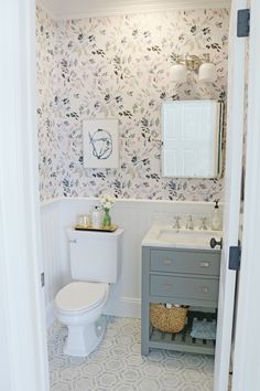 a white toilet sitting next to a sink in a bathroom under a mirror above a vanity