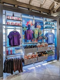 the inside of a sports store with shirts and shoes on display in front of glass windows