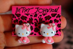 the hello kitty earrings are pink and black with white polka dots on it's ears