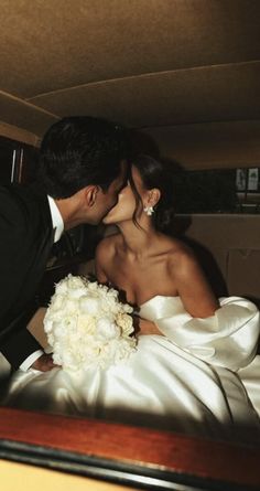 a bride and groom kissing in the back of a car