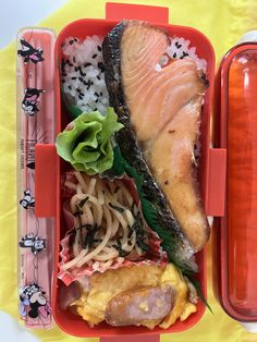 a bento box filled with sushi, noodles and salmon on top of rice