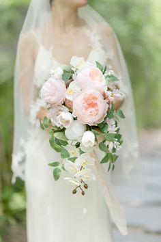 a bride holding a bouquet of pink and white flowers