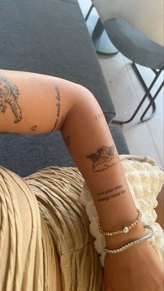 a woman's arm with tattoos on it sitting in front of a table and chair