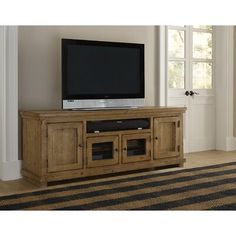 a flat screen tv sitting on top of a wooden entertainment center in a living room