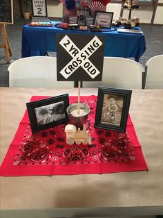 a table topped with pictures and candles on top of a red cloth covered tablecloth