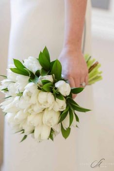 the bride's bouquet was made up of white tulips and greenery