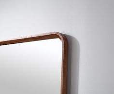 a mirror mounted to the side of a white wall next to a wooden framed object